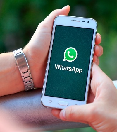 Duas mãos segurando um celular com a tela do WhatsApp